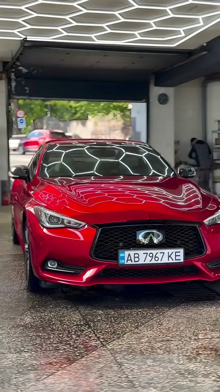 Червоний Infiniti Q60 після мийки у боксі VIP мийки під шестикутними LED-лампами